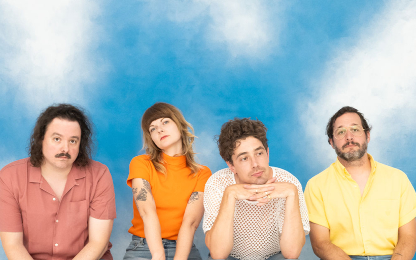 The band born ruffians sitting in front of a backdrop of clouds