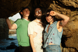 3 people standing in a cove by the ocean
