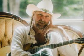 A man sitting in a chair with a guitar on his lap.